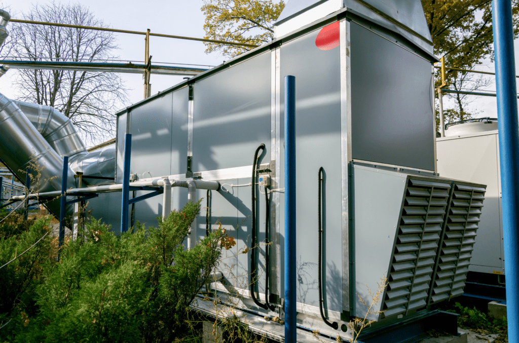 An Air-Handling Unit Outside Next To A Green Bush